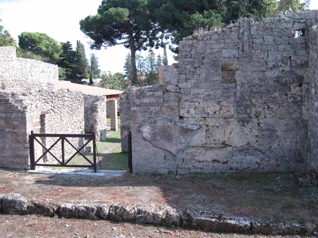I.5.2 Pompeii. September 2010. From entrance doorway, looking west along Vicolo del Conciapelle towards Via Stabiana. This also shows the portico wall of I.5.1. Along the wall between entrances I.5.2 and I.5.1 was a bench, and the remains of a street altar can be seen. Photo courtesy of Drew Baker.