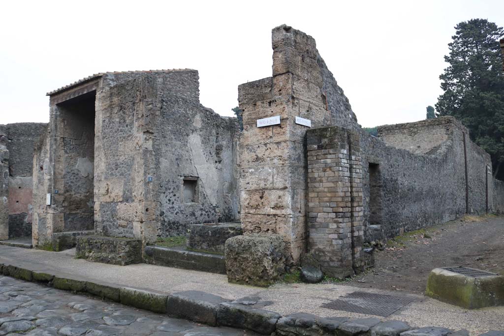 Street altar outside II.2.1 Pompeii. December 2018. 
Entrance doorway, centre left, on south side of Via dell�Abbondanza, with street altar in front, and water tower in Vicolo di Octavius Quarto, on right. 
Photo courtesy of Aude Durand.
