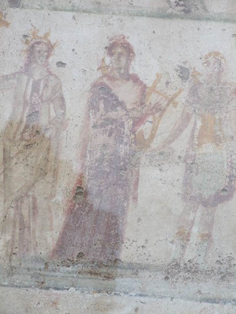 Detail of Apollo outside IX.11.1. December 2006. Apollo: Hair tied in knot, quiver behind shoulder, in brown Chiton and red coat, walking right but with head turned left, cithara held in left arm. See Lararien und Fassadenbilder in den Vesuvstadten by Thomas Frohlich, F66, page 335-337.