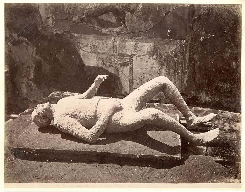 Known as Victim no.11, as this was the 12th to be successfully cast, and it was exhibited in the Antiquarium for some years.
He was found on 28th December 1882, at a height of approximately four metres from the original soil level.
According to Dwyer, he had been fleeing along the top of the cinders at the time of his death.
He was found above the south-west corner of a garden, now numbered as VIII.6.6.
Near him were found two iron keys.
See Dwyer, E., 2010. Pompeii’s Living Statues. Univ. of Michigan Press: (p.103), the twelfth victim: the man with two keys.
Garcia y Garcia gives the plaster cast number as 16.
See Garcia y Garcia, L., See Garcia y García, L., 2006. Danni di guerra a Pompei. Rome: L’Erma di Bretschneider. (p.194).
According to NdS –
“Insula 7, Reg. VIII. Inside and to the right of the fourth entrance on the north side, counting from the north-west, and at a height of about four metres from the soil, there appeared a human skeleton, of which was cast a model in gesso. Although the genitals do not appear, because they did not turn out, it seems from the features to be a man who, having fallen on his back, lies with his legs drawn up, his right hand to his breast, and his left arm somewhat raised. Near him were found two small iron keys, poorly preserved.”
See Notizie degli Scavi, 10, (1881-1882); p.606, (28th December 1862).