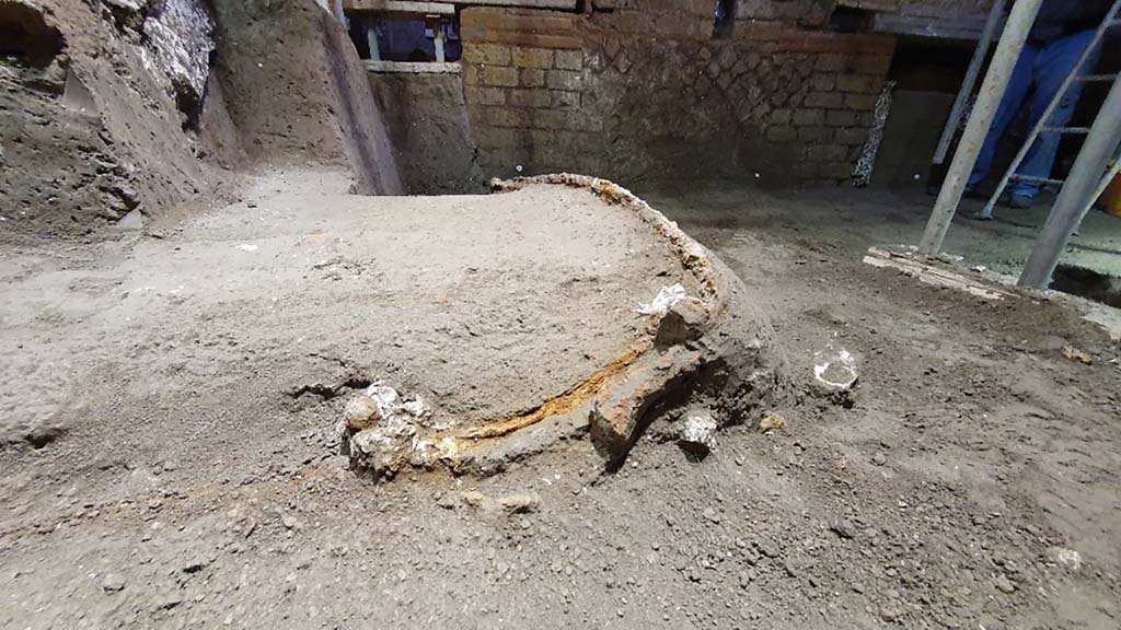 Cività Giuliana. February 2021. The excavation, which proceeded slowly over the following weeks due to the fragility of the elements which were progressively emerging, unearthed a ceremonial chariot, which had miraculously been spared by both the collapse of the walls and ceiling of the room and by the illegal activities, with tunnels passing it by on two sides, but without compromising the structure.

From the moment it was identified, the excavation of the chariot has proved to be particularly complex due to the fragility of the materials involved and the difficult working conditions; as a result, it was necessary to proceed by means of a micro-excavation conducted by the restorers of the Park, who are specialised in the treatment of wood and metals. At the same time, whenever a void was discovered, plaster was poured in as part of an attempt to preserve the imprint of the organic material that was no longer present. Consequently, it has been possible to preserve the shaft and platform of the chariot, as well as the imprints of ropes, thus revealing the chariot in all of its complexity.

Cività Giuliana. Febbraio 2021.  Lo scavo proseguito lentamente nelle settimane successive – per la fragilità degli elementi che si progressivamente emergevano, ha portato alla luce un carro cerimoniale, risparmiato miracolosamente sia dai crolli delle murature e delle coperture dell’ambiente sia dalle attività clandestine, che con lo scavo di due cunicoli lo hanno sfiorano su due lati, senza averne compromessa la struttura.

Sin dal momento della sua individuazione lo scavo del carro si è rivelato particolarmente complesso per la fragilità dei materiali e le difficili condizioni di lavoro; si è quindi dovuto procedere con un vero e proprio microscavo condotto dalle restauratrici del Parco specializzate nel trattamento del legno e dei metalli. Parallelamente, ogni volta che si rinveniva un vuoto, è stato colato del gesso per tentare di preservare l’impronta del materiale organico non più presente. Così si è potuto conservare il timone e il panchetto del carro, ma anche impronte di funi e cordami, restituendo così il carro nella sua complessità.

Photograph © Parco Archeologico di Pompei.
