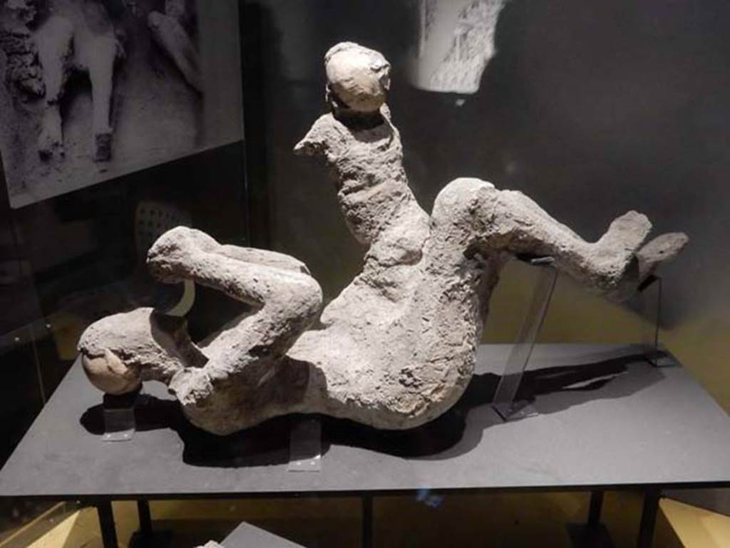 VI.17.42, Pompeii, May 2018.
Plaster cast of a man (52) and child (51) found in the corridor leading to the garden area. Photo courtesy of Buzz Ferebee.
According to Estelle Lazer, this individual (52) is clearly a mature adult, but there is insufficient evidence to make an attribution of the sex of this victim.
See Lazer E., et al. 2020. Inside the Casts of the Pompeian Victims: Results from the First Season of the Pompeii Cast Project In 2015. Papers of the British School at Rome.
Victim 51 is a male child aged less than 6 years, probably 5 to 6 years old.
The body was found under staircase 30 of the Casa dell Bracciale d’Oro between the 3rd and 6th of June 1974.
Imprints from a tunic are vaguely identifiable on the chest, shoulders, back and legs of the victim.
See Osanna, N., Capurso, A., e Masseroli, S. M., 2021. I Calchi di Pompei da Giuseppe Fiorelli ad oggi: Studi e Ricerche del PAP 46, p. 439-440, Calco n. 51.
Victim 52, previously identified as female, is now identified as a male aged not less than 20 years old.
The body was found under staircase 30 of the Casa dell Bracciale d’Oro between the 3rd and 6th of June 1974.
Imprints from the clothing are vaguely identifiable on the torso and legs.
See Osanna, N., Capurso, A., e Masseroli, S. M., 2021. I Calchi di Pompei da Giuseppe Fiorelli ad oggi: Studi e Ricerche del PAP 46, p. 441-443, Calco n. 52.