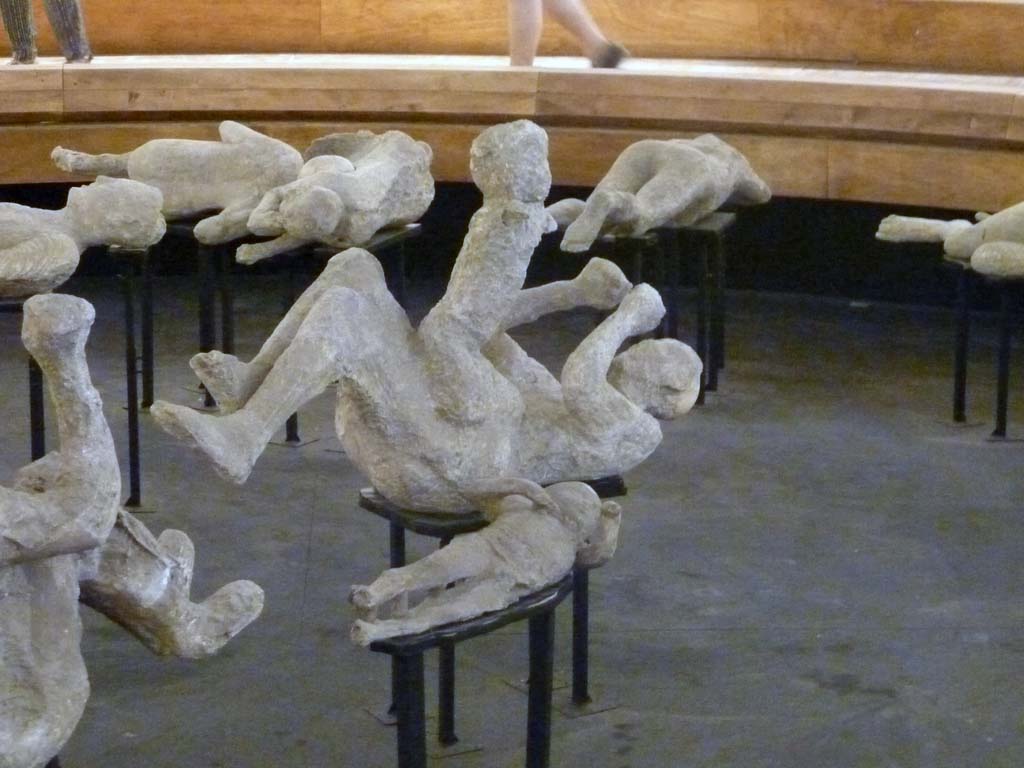 VI.17.42 Pompeii. Victims 51, 52 and 53 on display in the pyramid in the amphitheatre, September 2015.
Plaster-casts previously believed to be a mother and two children in the family group of four.
The group of four is now identified as four males.