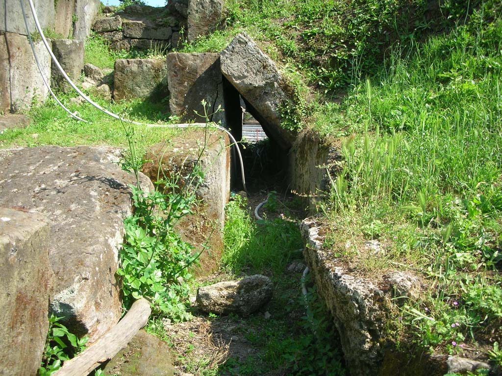Porta di Nocera or Nuceria Gate, Pompeii. May 2010.
Looking south along course of drain on west exterior side of gate. Photo courtesy of Ivo van der Graaff.
According to Van der Graaff –
“The drains are less conspicuous and a practical necessity.
Even today, the characteristic sudden downpours of the region can turn the streets into small torrents draining water from much of the city.
Each gate on the downslope side of Pompeii was a natural drain because they tend to be on the topographical depressions that formed the easiest access routes into the city. Rather than having the water pass through the gates, authorities eventually built formal drains through the agger.
At Porta Stabia, Nocera and Sarno, engineers would modify basalt street pavers to direct runoff waste into the sewers passing next to the gate to keep the passageways free of wastewater (Note 110). …………………….
Most gates indicate that drainage concerns were already current in the late second century BCE, if not earlier.
The Porta Nocera preserves a drain on its western flank.
Due to its relative height, it clearly predates the lowering of the road passing through it – an event that occurred in the Augustan period.
The drain remained in use as engineers altered the flagstones in the road to channel the water into the sidewalk farther uphill (Note 115).”
See Van der Graaff, I. (2018). The Fortifications of Pompeii and Ancient Italy. Routledge, (p.103-104, Notes 110 and 115).