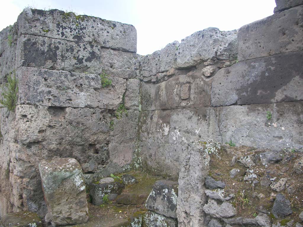 Vesuvian Gate Pompeii. May 2010. Looking south-west at north end of west wall. Photo courtesy of Ivo van der Graaff.
According to Van der Graaff –
“The Porta Vesuvio displays the remains of two altars in the cul-de-sac on the exterior north-west tip of the gate.
Upon excavation in the early twentieth century, it preserved the remains of a plaster coating and a fresco associated with the altars.
Any identifiable signs had already deteriorated beyond recognition and have now completely disappeared.
Antonio Sogliano identified the shrine as a lararium and the fresco presumably depicted the public lares protecting the city (Note 18).
However, given the prevalence of Minerva on the other gates, it seems plausible to assume that she played a role here as well.”
See Van der Graaff, I. (2018). The Fortifications of Pompeii and Ancient Italy. Routledge, (p.211 and Note 18).