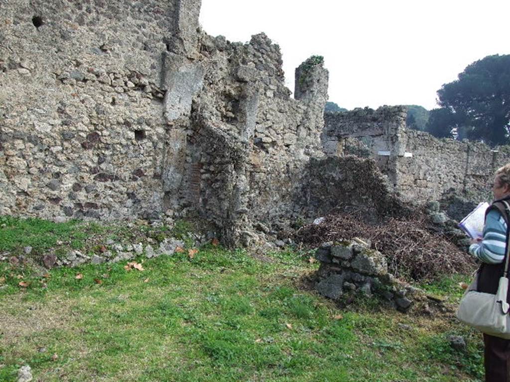 I.2.3 Pompeii. December 2006. Looking across the garden area, towards the remains of the two rooms in the south-east corner. According to Fiorelli, on the opposite side of the garden from the vestibule and bedroom, was a storeroom and a room uniquely used for the sacred domestic Gods (Sacellum). A brick altar was in the middle, on which was painted a cock. The image of the Genius was painted on the wall pouring a libation onto the altar. Nearby was a large serpent, plants, and it was surmounted by garlands with small birds.
See Pappalardo, U., 2001. La Descrizione di Pompei per Giuseppe Fiorelli (1875). Napoli: Massa Editore. (p.34).
According to Boyce, on the south side of the Viridarium were two small adjoining rooms. One was a storeroom and the other, according to Fiorelli, was devoted only to the service of the domestic cult. In the centre of the room entered from the first door stood a masonry altar, on which was painted a cock. On the south wall a panel of white stucco was marked off with red stripes and within it was the Lararium painting.
The Genius poured a libation upon an altar, towards which a large serpent moved, moving through plants. Across the top were three small festoons, on each of which perched a little bird.
See Boyce G. K., 1937. Corpus of the Lararia of Pompeii. Rome: MAAR 14. (p.21 No.4)