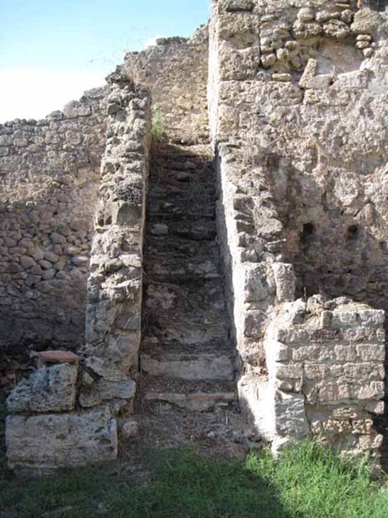 1.2.6 Pompeii. September 2010. Looking north to steps to upper floor, from north portico.
On the right is the arched niche in the north wall of the kitchen on the upper floor. Photo courtesy of Drew Baker.
According to Boyce –
“In a small room, perhaps a kitchen on the intermediate floor, reached by stairs on north side of peristyle, was a Lararium.
Below a small arched niche, a rectangular panel was marked off and within it was painted a single serpent advancing left towards the offerings upon an altar: in the background were plants and across the top were festoons.”
See Boyce G. K., 1937. Corpus of the Lararia of Pompeii. Rome: MAAR 14. (p.21 no.5).
Note: Found in the kitchen located on the first floor was a bronze statuette of Diana with bow and quiver. Giornale degli Scavi, N.S. III, 1874, 58.
See Giacobello, F., 2008. Larari Pompeiani: Iconografia e culto dei Lari in ambito domestico. Milano: LED Edizioni, (p.132, no.3)