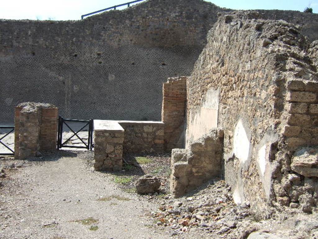 I.2.13 Pompeii. September 2005. Taken from rear. Looking west towards site of ruined small rear room or cupboard, and bar-room onto Via Stabiana and the Little Theatre. On the left, behind the brick pilaster separating two doorways, would have been the site of the south wall of I.2.13. I.2.14 is visible on the extreme right of the picture.
