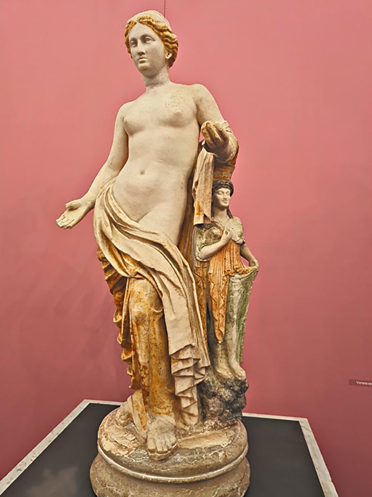 I.2.17 Pompeii. October 2023.
Statuette of Venus from Room 13, east wall, found in March 1873.
Now in Naples Archaeological Museum. Inventory number 109608.
On display in “L’altro MANN” exhibition, October 2023. Photo courtesy of Giuseppe Ciaramella.
According to Fiorelli –
“Found in a niche faced with marble, this standing statuette of Venus leaning against her idol, still keeping the colours in which it had been painted.”
See Pappalardo, U., 2001. La Descrizione di Pompei per Giuseppe Fiorelli (1875). Napoli: Massa Editore. (p.36)