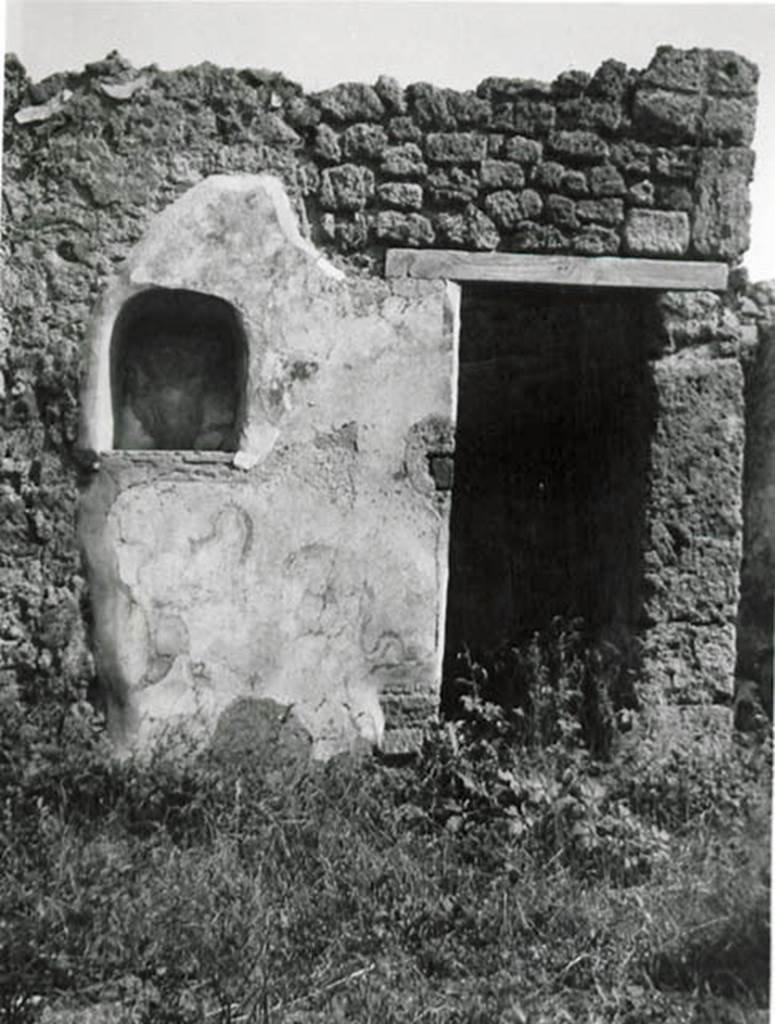 I.2.24 Pompeii. 1935 photo taken by Tatiana Warscher.
Looking towards south wall of atrium, with niche and doorway to understairs area.
See Warscher T., 1935. Codex Topographicus Pompeianus: Regio I.2. (no.45), Rome: DAIR, whose copyright it remains.
According to Boyce, on the south side of the atrium was the lararium.
Above an arched niche (h.0.60, w.0.52, d.0.23, h. above floor 1.35) was painted a cylindrical altar (tripod according to Fiorelli) with a Genius pouring a libation.
Standing beside him was the tibicen and to the left was a Lar. The Lar on the right was not preserved.
Below the niche were the two serpents.
On the wall on each side of the niche was painted a large dog?
The one on the left was poorly preserved but was seen to be lying down, while the one on the right was opening his mouth wide.
From the hindquarters of this second dog there projected horizontally the upper half of the body of a man.
See Boyce G. K., 1937. Corpus of the Lararia of Pompeii. Rome: MAAR 14. (p.23, no.16 and Pl.2,2)
See Sogliano, A., 1879. Le pitture murali campane scoverte negli anni 1867-79. Napoli: Giannini. (p.17, no.46).