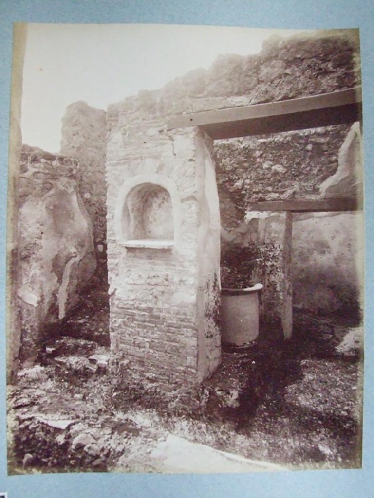I.3.30 Pompeii. Lararium in peristyle at foot of straight flight of stairs.
Old undated photograph courtesy of the Society of Antiquaries, Fox Collection.
According to Boyce –
in the west wall of the peristyle was an arched niche (h.0.55, w.0.50, d.0.27, h. above floor 1.30).
Its walls were adorned with painted flowers.
On the wall on either side of it, was painted a Lar, 34cms high, holding rhyton and situla.
Below it, there was a single serpent moving towards an altar.
See Boyce G. K., 1937. Corpus of the Lararia of Pompeii. Rome: MAAR 14. (p. 24)
See Giacobello, F., 2008. Larari Pompeiani: Iconografia e culto dei Lari in ambito domestico. Milano: LED Edizioni, (p.135, no.7)