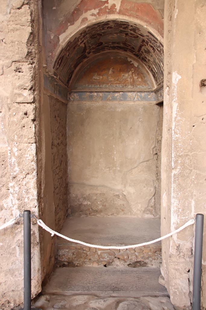 I.6.4 Pompeii. October 2022.
Room 16, looking south into sacellum in south-west corner of atrium. Photo courtesy of Klaus Heese.
According to Boyce –
On the right of the tablinum is a recess with vaulted ceiling and a figures frieze running around three walls.
This frieze depicts scenes from the Iliad with figures in white stucco relief upon a ground of blue.
It has been suggested, without very good reason, that this room was the lararium.
He quoted Not. Scavi, 1913, 28.
See Boyce G. K., 1937. Corpus of the Lararia of Pompeii. Rome: MAAR 14. (p.25, no.37).