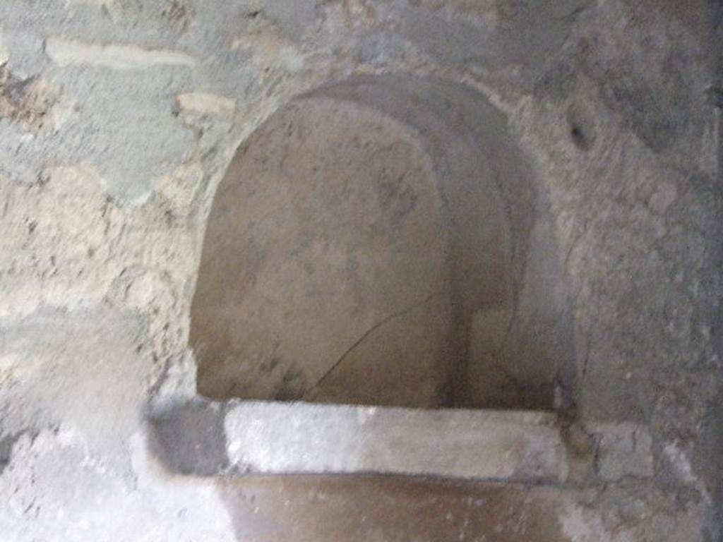 I.11.14 Pompeii. December 2006. Niche in north wall of kitchen. According to Giacobello, this arched niche located near to the bench was covered in white stucco with a protruding brick ledge. See Giacobello, F., 2008. Larari Pompeiani: Iconografia e culto dei Lari in ambito domestico. Milano: LED Edizioni. (p.151)