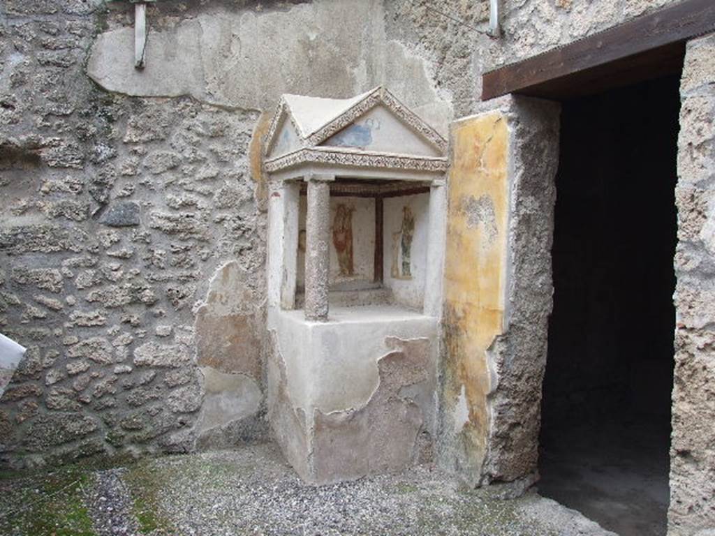 I.16.3 Pompeii. December 2006. Lararium on west side of atrium.
On the left is a painting of the Genius with cornucopia and an offering plate over a round altar round which a serpent is coils.
On the right is Minerva with shield and lance and an offering plate over a round altar.
See Fröhlich, T., 1991. Lararien und Fassadenbilder in den Vesuvstädten. Mainz: von Zabern. (p.264, L35, taf.5.2-3).
See Giacobello, F., 2008. Larari Pompeiani: Iconografia e culto dei Lari in ambito domestico. Milano: LED Edizioni, (p.234, no.A6)