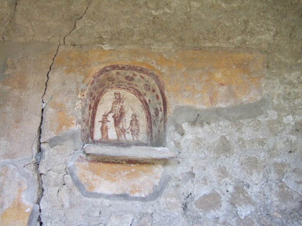 I.17.4 Pompeii. May 2006. Lararium niche on west wall of peristyle garden.
A genius is making an offering at a round altar. A small camillus is to his left.
The side walls are painted with red flowers possibly roses.
On the yellow-coloured wall outside the niche, a colour trail is visible on the right, which perhaps belongs to a big snake. A paint ridge above the niche may perhaps be interpreted as a garland.
See Fröhlich, T., 1991. Lararien und Fassadenbilder in den Vesuvstädten. Mainz: von Zabern, L37, p. 264, taf. 9,1.