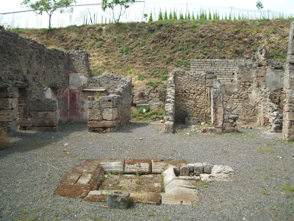 V.2.g Pompeii. May 2005. Looking north across room ‘b’ the atrium, to entrance corridor ‘a’, in centre.
The doorways to room ‘i’, room ‘f’ the kitchen, and room ‘e’ the cubiculum, can be seen on the left of the entrance corridor.
The doorways to room ‘c’ with two entrances separated by a pillar, and room ‘d’ in the north-east corner, can be seen on the right of the entrance corridor.
According to NdS, on the pilaster dividing the fauces (room ‘a’) from the cubiculum on the left of it (room ‘e’), facing south across the atrium, was a lararium niche covered in white plaster.
On the left side of the lararium was a doorway into a cubiculum, room ‘e’.
See Notizie degli Scavi di Antichità, 1896, (p.419)
According to Boyce, only the pilaster between the fauces and the room to the west had a decorated upper part.
In this pilaster, at a height of I.68m, was a niche for the household gods.
This was coated with white stucco and painted in the Third Style.
See Boyce G. K., 1937. Corpus of the Lararia of Pompeii. Rome: MAAR 14. (p.36, no.104)
According to CTP, the niche at the south-west terminus of the fauces facing the atrium is now lost. (1982).
See Van der Poel, H. B., 1986. Corpus Topographicum Pompeianum, Part IIIA. Austin: University of Texas. (p.72)