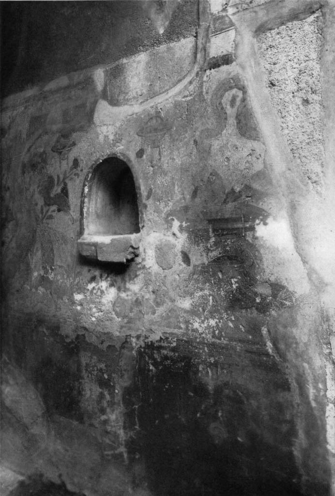 V.2.h Pompeii. c.1930s. In the east wall of the entrance fauces ‘a’ an arched niche can be seen.
According to Boyce, this had a projecting floor and its walls were covered with white stucco.
It was outlined, inside and outside, with red stripes.
The wall beside the niche was painted with the serpents.
To the right of, and below the niche, was painted an unusual altar, resembling a brazier of bronze (see note below*).
Its upper surface was circular and had two handles at the sides.
One of the huge serpents had its body coiled around this altar and was raising its head to the offerings.
The second serpent was painted on the wall to the left of the niche and was raising its head to the niche rather than the altar.
The background was white and adorned with plants, across the top were painted garlands hanging from painted nails.
See Boyce G. K., 1937. Corpus of the Lararia of Pompeii. Rome: MAAR 14. (p. 36, no. 106, pl.10,1)
*Boyce added a note on p. 37 that said a similar brazier was found with the painting of the serpents in I.7.10-12.