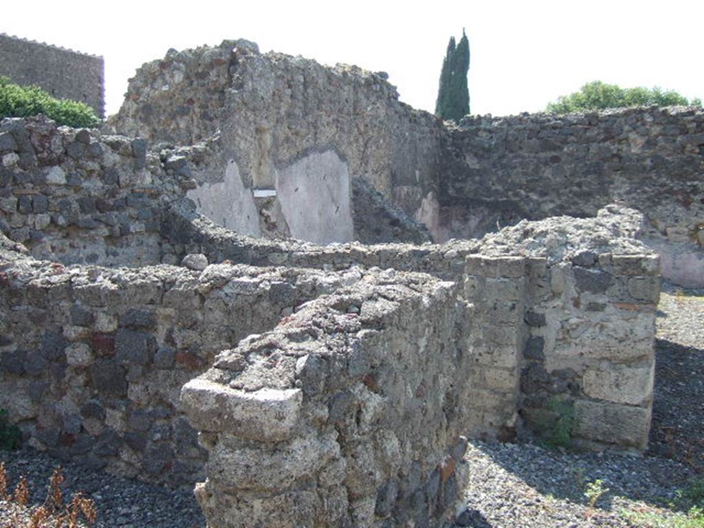 VI.2.28 Pompeii. September 2005. Looking south-west towards rear of house and small garden area. The remains of two cubicula can be seen on the left, and in the upper middle would have been the Oecus.
On the south wall of the oecus, the lararium niche can be made out, above a white shelf. At the rear of the oecus, across the rear of the house, would have been the garden area. According to Giacobello, in the south wall of the Oecus was a square niche with the residue of white plaster and shelf in marble. See Giacobello, F., 2008. Larari Pompeiani: Iconografia e culto dei Lari in ambito domestico. Milano: LED Edizioni. (p.290)
According to Boyce, in the south wall of the oecus which opens off the garden is a rectangular niche. The walls of the niche are coated with stucco and painted green. The floor of the niche is a thick slab of marble; the reports called it la nicchia per I Penati. See Boyce G. K., 1937. Corpus of the Lararia of Pompeii. Rome: MAAR 14. (p.44, no.143)