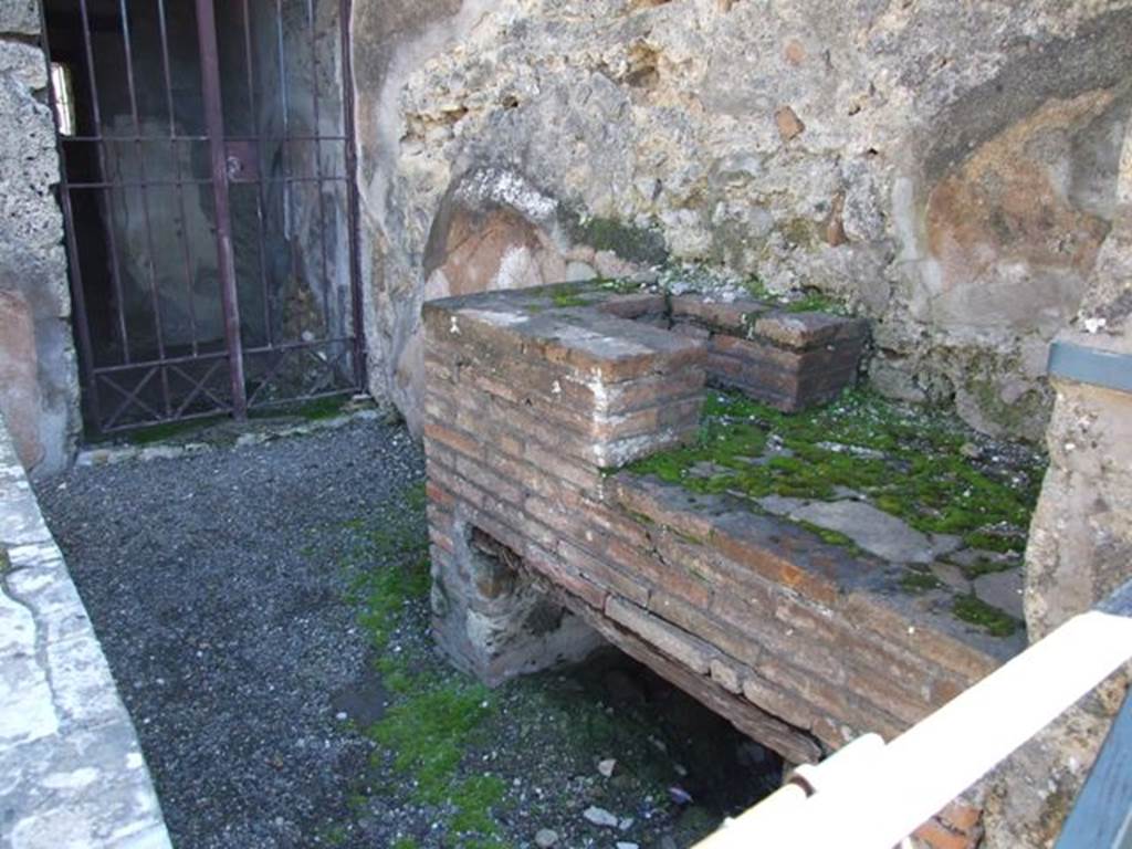 VI.10.1 Pompeii. March 2009. South wall of caupona with hearth and doorway to rear room on south side. According to Eschebach, the stairs to the upper floor would have been against this south wall. Where the modern gate has been fitted, there may be a mark showing the steps leading up the wall.