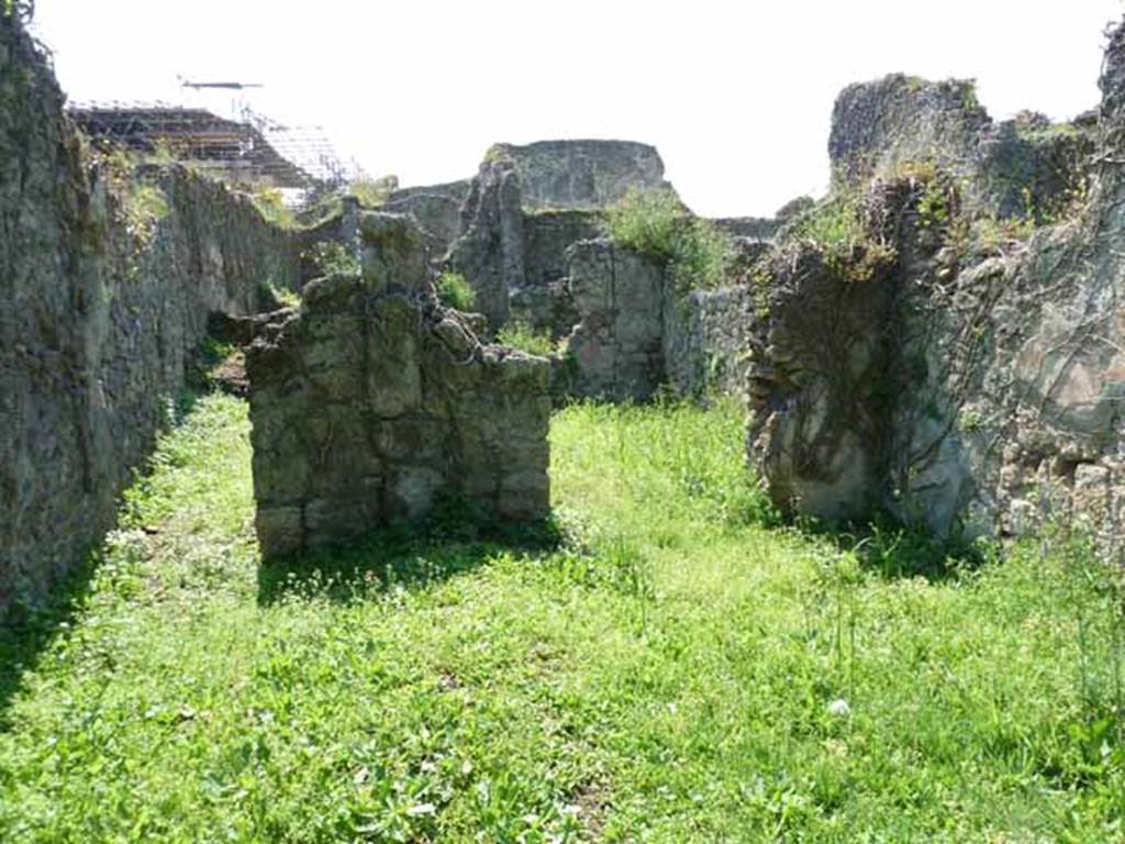 VI.16.11 Pompeii. May 2010. Looking west across shop to corridor to rear, on left, and rear room in north-west corner, on right. Originally, on the west wall between the corridor and the rear room was a lararium. According to Boyce, there was a ruined niche in the west wall, coated with white stucco bordered with red stripes. Red and green garlands were painted on the back wall of it. See Notizie degli Scavi di Antichità, 1908, p. 58. See Boyce G. K., 1937. Corpus of the Lararia of Pompeii. Rome: MAAR 14. (p. 58, no.222).