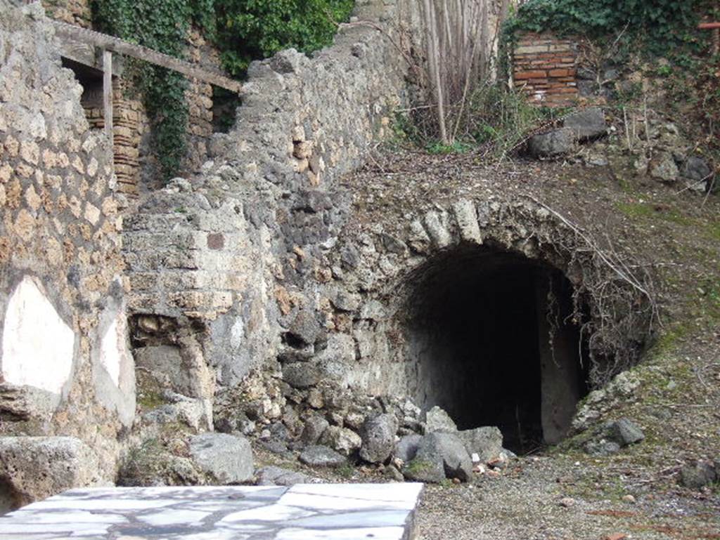 I.2.15 Pompeii. December 2005. Vaulted cistern partly visible from I.2.14. The brick wall at the top of the slope above the cistern marking the end of the corridor from the atrium, together with the remains of the stairs, are the only remains of the area at the west end of the house, that is � steps to upper floor, cupboard, small stable, kitchen and latrine.