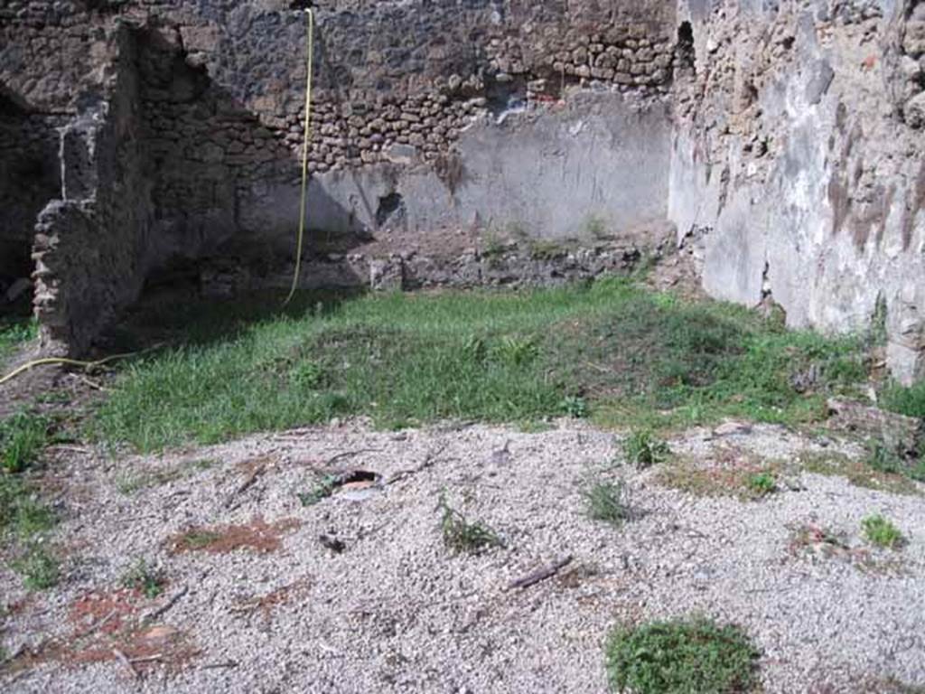 I.2.24 Pompeii. September 2010.
Looking north across site of summer triclinium and peristyle, from south portico. Photo courtesy of Drew Baker.
According to Jashemski, this Caupona or Officina Libraria had a portico on the south and east sides of the garden area.
The columns were connected by a low wall with an entrance to the garden on the west.
The caupona was excavated in 1873. There was a masonry triclinium with a table in the garden.
Two large breaks in the triclinium, which is today badly damaged, reveal the amphorae used in its construction.
Fiorelli believed that the low podium along the north wall held pots of flowers.
Mau reported a drainage channel at the corner of the triclinium, but it is no longer visible.
Only the base of an aedicula lararium built against the east wall opposite the north end of the east couch can still be seen.
See Jashemski, W. F., 1993. The Gardens of Pompeii, Volume II: Appendices. New York: Caratzas. (p.25)
According to Boyce, in the east wall of the peristyle, above one of the beds of a masonry triclinium was a niche.
It was described by Fiorelli as a sacrario.
More fully described by Mau as an “aedicula, una base, con una piccola tavola, che sta in una specie di nicchia coperta a volta, e probabilmente conteneva un’idolo”.
There remains now only the solid base, (0.40 by 0.32, h.0.65) and on the wall above it, the marks left by a vaulted structure which rested on the base.
Bull. Inst, 1874, 262; Fiorelli, Descr., 47.
See Boyce G. K., 1937. Corpus of the Lararia of Pompeii. Rome: MAAR 14. (p.23, no.17)
As this book was written in the 1930s, it is probable that there is now even less evidence of the niche, following the bombing in the near vicinity in 1943, and the damage of the 1980 earthquake.
Possibly the solid base may be visible on the extreme right of the above photo, but would need a clearer photo.
If the white lapilli is covering the site of the triclinium, then the stone in the photo would seem to be in the correct place, “against the east wall opposite the north end of the east couch”, but according to Boyce’s measurements appears to look too small.