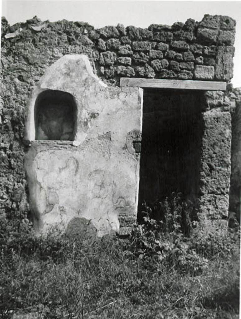I.2.24 Pompeii. 1935 photo taken by Tatiana Warscher.
Looking towards south wall of atrium, with niche and doorway to understairs area.
See Warscher T., 1935. Codex Topographicus Pompeianus: Regio I.2. (no.45), Rome: DAIR, whose copyright it remains.
According to Boyce, on the south side of the atrium was the lararium.
Above an arched niche was painted a cylindrical altar (tripod according to Fiorelli) with a Genius pouring a libation.
Standing beside him was the tibicen and to the left was a Lar. The Lar on the right was not preserved.
Below the niche were the two serpents.
On the wall on each side of the niche was painted a large dog?
The one on the left was poorly preserved but was seen to be lying down, while the one on the right was opening his mouth wide.
From the hindquarters of this second dog there projected horizontally the upper half of the body of a man.
See Boyce G. K., 1937. Corpus of the Lararia of Pompeii. Rome: MAAR 14. (p.23, no.16 and Pl.2,2)
See Sogliano, A., 1879. Le pitture murali campane scoverte negli anni 1867-79. Napoli: Giannini. (p.17, no.46).