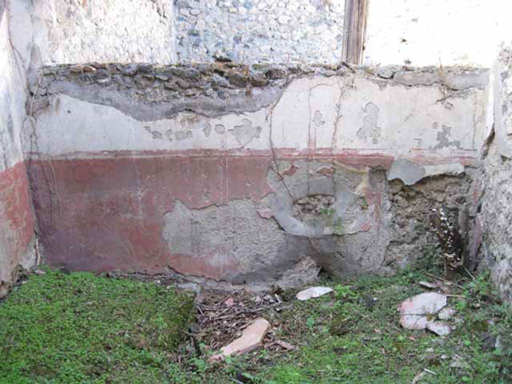 I.2.28 Pompeii. September 2010. North wall of room on south side of triclinium, with window onto garden area. Photo courtesy of Drew Baker.
According to Fiorelli, this room had access to a short underground passage for keeping provisions. See Pappalardo, U., 2001. La Descrizione di Pompei per Giuseppe Fiorelli (1875). Napoli: Massa Editore. (p.37)
According to Warscher, quoting Mau in Bull. Inst, 1874, p.250/51, she wrote �
�Il peristilio, situate piu alto dell atrio a causa del terreno inuguale, ha corridoi di 3 e 3 colonne sui lati S ed E, mentre verso N ed O confina con le case adiacenti (I.2.17; I.2.22; I.2.24).  
Le colonne sono di mattoni e di stucco rozzo, color di carne fino all�altezza del muriciuolo che le congiunge, bianco di sopra.
La parte occidentale del portico meridionale, posteriormente soltanto, come ci fa testimonianza lo stucco delle colonne, coperto dal muro, ne fu separato e trasformata in una camera, che mediante una porta corrisponde colla camera a sinsitra del tablino, mentre verso N con una finestra larga, distante dal suolo m.1,52, si apre sul peristilio.
Sotto il pavimento di questa camera v�� un cavo, largo m. 0,98 + 0,67, profondo m. 1,32, rivestito di stucco e di sopra a met� coperto, mentre l�apertura che rimane evidentemente doveva chiudersi con un coperchio.
Sifatto cavo, il primo di questa sorta che si sia trovato a Pompei, serviva senza dubbio per conservare tutto ci�, cher si voleva difendere dal caldo, facendo cos� le veci d�una piccola cantina.
Sul lato meridionale del peristilio vi � ancora un armadio stretto, aperto verso O, ed il cui fondo viene formato dal muro occidentale della camera a destra dell�atrio, la quale sporge un poco nel peristilio�.

