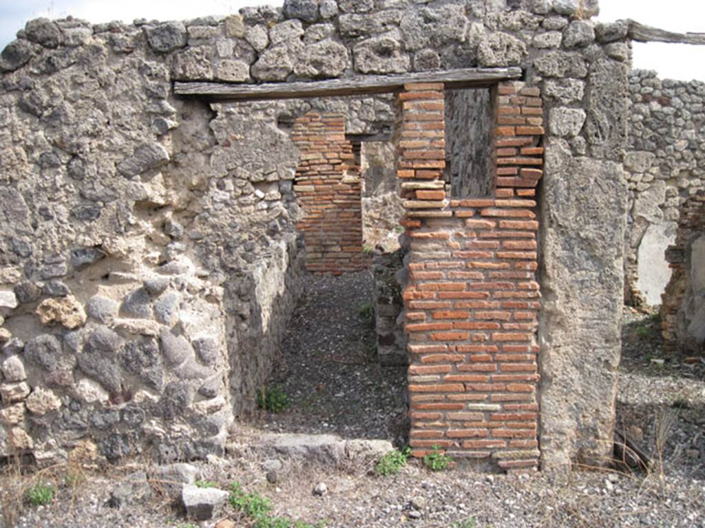 I.3.8b Pompeii. September 2010.
Looking east towards south-central doorway from east portico of peristyle, towards kitchen at rear. Photo courtesy of Drew Baker.
According to Boyce, somewhere along the east wall of the peristyle was a niche.
In the niche, a terracotta statuette of Minerva was found.
She was wearing a helmet and holding a shield on her left arm and holding a patera in her right hand.
See Boyce G. K., 1937. Corpus of the Lararia of Pompeii. Rome: MAAR 14. (p.24, no.22)
Giornali degli Scavi, N.S. I, 1869, p. 301.
Boyce gave a note 1 on page 24, to this entry. It read –
In a room opening off the east side of the peristyle a bronze statuette of Fortuna was found.
She was holding a cornucopia against her left shoulder.
Giornali degli Scavi, N.S., i, 1869, 305.
According to Giacobello – the niche is no longer conserved.
See Giacobello, F., 2008. Larari Pompeiani: Iconografia e culto dei Lari in ambito domestico. Milano: LED Edizioni, (p.252, no.V3)