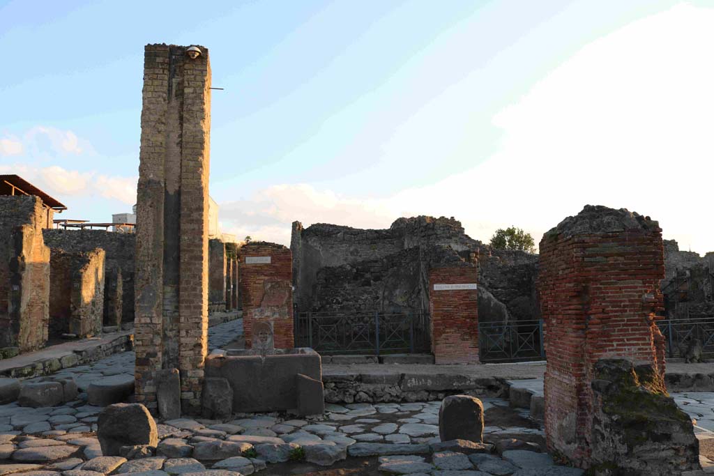 I.4.15 Pompeii. December 2018. Looking east across Holconius� crossroads on Via Stabiana, towards I.4.15 behind fountain at south-east corner of crossroads. 
Photo courtesy of Aude Durand.
