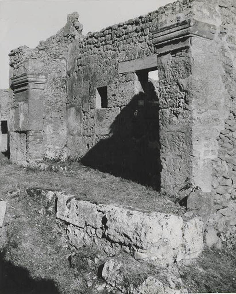 10501-warscher-codex-91-640.jpg
I.5.1 Pompeii. 1936, taken by Tatiana Warscher.
Looking east along front façade on north side of insula on Vicolo del Conciapelle.
Warscher quoting from Sogliano’s Giorn. Sc. 1874, III, p.8 described –
“I.5.1. Cominciandone la descrizione dal lato settentrionale, incontriamo, a partire dall’angolo nord-ovest, una bottega con piccola abitazione del padrone. Essa è preceduta da una specie di vestibolo, formato da un tettoja, che è sostenuta da un lungo architrave di m. 5,40, poggiato sopra due pilastri finienti con capelli molto semplici.
La lungezza di questo architrave, che è uno dei più lunghi trovati finora, e l’opus incertum mi fanno credere tale aggiunta molto posteriore all’originaria costruzione della bottega, che sul muro d’ingresso specialmente presenta grosse lastre del tufo di Sarno. Varcata la soglie di pietra vesuviana, munita dei soliti incavi, troviamo sul lato sinistro due cubicoli finestrati, dei quali l’uno è perfettamente rozzo e l’altro avente sulla soglia un cardine di ferro, mostra lievi tracce di una semplicissima decoratione. Nella bottega sul muro a destra vi è praticato un canale per lo scopo delle acque, e in fondo si trova un dietrobottega. Credo che il vestibolo suindicato si sia usato per la vendita delle merci.
Addossata al lato opposto del pilastro sinistro sta un’ara rivestita di stucco con due rialzi arrontodati (arrotondati) al di sopra”.
(translation: “beginning the description from the north side, we meet in the north-west corner, a shop with small house of the master. It is preceded by a vestibule, formed with a roof, which was backed by a long lintel (architrave) of 5.40m, resting above two pilasters finished with simple capitals. The length of this lintel, which was one of the longest so far found, and the opus incertum makes me believe that this goes back to the original construction of the shop, which shows big slabs of Sarno tufa on the entrance wall. Crossing the threshold of vesuvian stone, furnished with the usual notches, we find two windowed cubiculums on the left side, of which one is completely rough and the other had an iron hinge on the threshold (doorstep), showing faint traces of a simple decoration. On the wall on the right of the shop, there was a channel for the purpose of water, and at the back we find a rear room. I think the vestibule above was used for the sale of goods. Backing onto the opposite side of the left pilaster was an altar covered in stucco, with two rounded prominences above". )
From Mau, in Bull. Inst, 1875, p.25, she quoted –
“Sono perfettamente d’accordo coll’autore della descrizione del G.Sc. nell’attribuire ad’un’epoca relativamente recente quel singolare vestibolo che sta avanti all’ingresso della detta bottega”.
(translation: I agree with the author of the description in G. Sc. in the attribute of a relatively recent time to that singular vestibule which stands in front of the entrance to the said shop).
See Warscher T., 1936. Codex Topographicus Pompeianus: Regio I.1, I.5. (no.16), Rome: DAIR, whose copyright it remains.