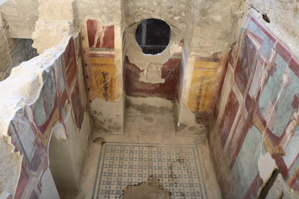 .6.2 Pompeii. December 2018. Frigidarium of baths’ area.
Looking down on west wall and circular window through into corridor in east wing of cryptoporticus. Photo courtesy of Aude Durand.
There is a niche in west wall with paintings of candelabra and cupid at its sides.
At the rear through the circular window the west wall of the east wing of the cryptoporticus can be seen.

