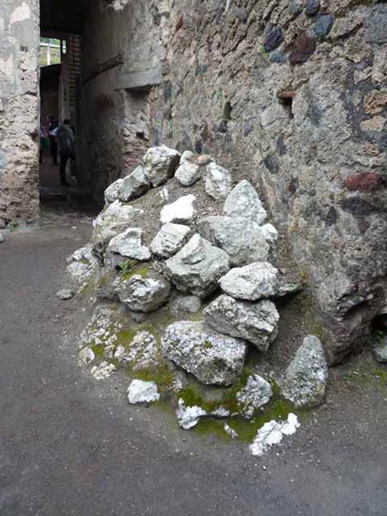 I.6.4 Pompeii. May 2010. Room 9, east side of small garden area with remains of ancient building material. Looking north towards corridor to atrium.