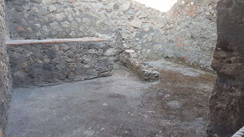 .6.4 Pompeii. August 2023.
Room 8, looking through doorway towards east wall with hearth, on left, and latrine, on right. Photo courtesy of Maribel Velasco.