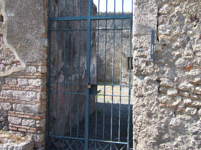 I.7.11 Pompeii. December 2006. South end of house, north wall of north portico with reproduction wooden doors, leading from I.7.12. According to Jashemski, Maiuri said the space between the columns and the west pillar of the portico were closed by glass set in a wooden frame. This would have kept the rain and sun from the triclinium, tablinum and exedra. Maiuri did not mention finding any glass and some scholars think that wooden shutters were used. See Jashemski, W. F., 1993. The Gardens of Pompeii, Volume II: Appendices. New York: Caratzas. (p.38)
From now on, the photos show the northern part of this house, starting from the north wall of the north portico. To see the southern part of the house and garden area, see I.7.12
