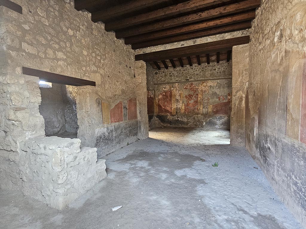 I.10.1, Pompeii. November 2024.
Looking south along east wall of atrium with doorway to oecus and steps to upper floor, on left. Photo courtesy of Annette Haug.
