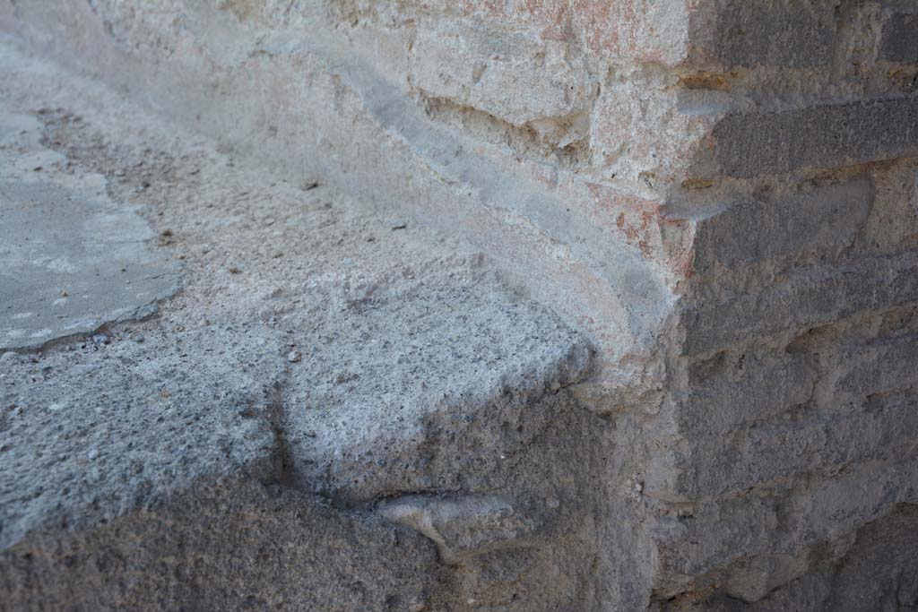 I.10.18 Pompeii. April 2017. Detail of remaining painted plaster at north end of bench seating on south side of entrance doorway.
Photo courtesy Adrian Hielscher.