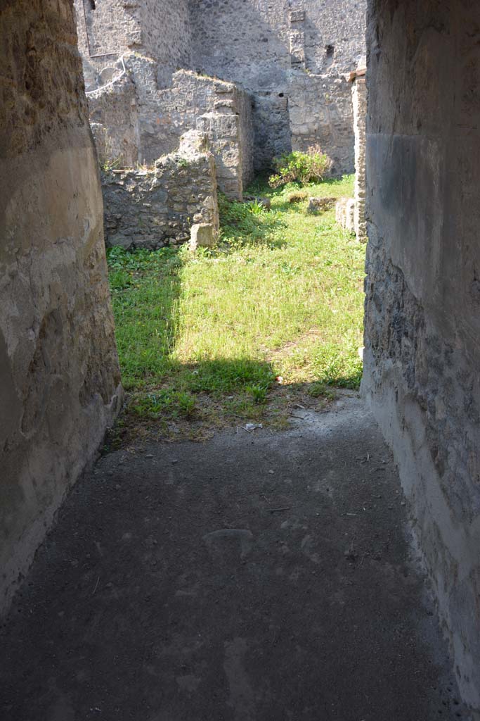 I.10.18 Pompeii. April 2017. Looking west from entrance corridor/fauces.
Photo courtesy Adrian Hielscher.
“The entrance doorway enters through the spacious entrance corridor with rustic flooring and walls covered with fine black plaster, into a small tuscanic atrium. Opening, on either side of the entrance corridor, were rooms 2 and 3, both with door-jambs painted in red, both lit by a rectangular window which opened in the east wall overlooking the roadway.
The room to the left of the fauces/corridor (room 2), probably a cubiculum, was decorated with a low light red zoccolo topped with a narrow red band edged by white lines and decorated with white geometric patterns. The upper area of the wall was simple white rough plaster.
The room to the right (room 3) was an oecus, it was decorated with a high pink zoccolo, above which the part of the wall had been left of rustic white plaster, equally rustic was the flooring.”
See Notizie degli Scavi, 1934, (p.341-4)