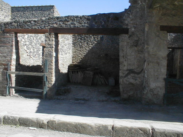 I.11.4 Pompeii. May 2005. Entrance to small shop. According to NSc, a human skeleton was found high up in the ash level on 18th August 1913, in front of number 4. Many coins were found with the skeleton, including 18 silver, 5 large bronze and 43 medium bronze. See Not. Scavi, 1913, pp.309-10, and described as Reg. II, insula 1 davanti n.4. 
