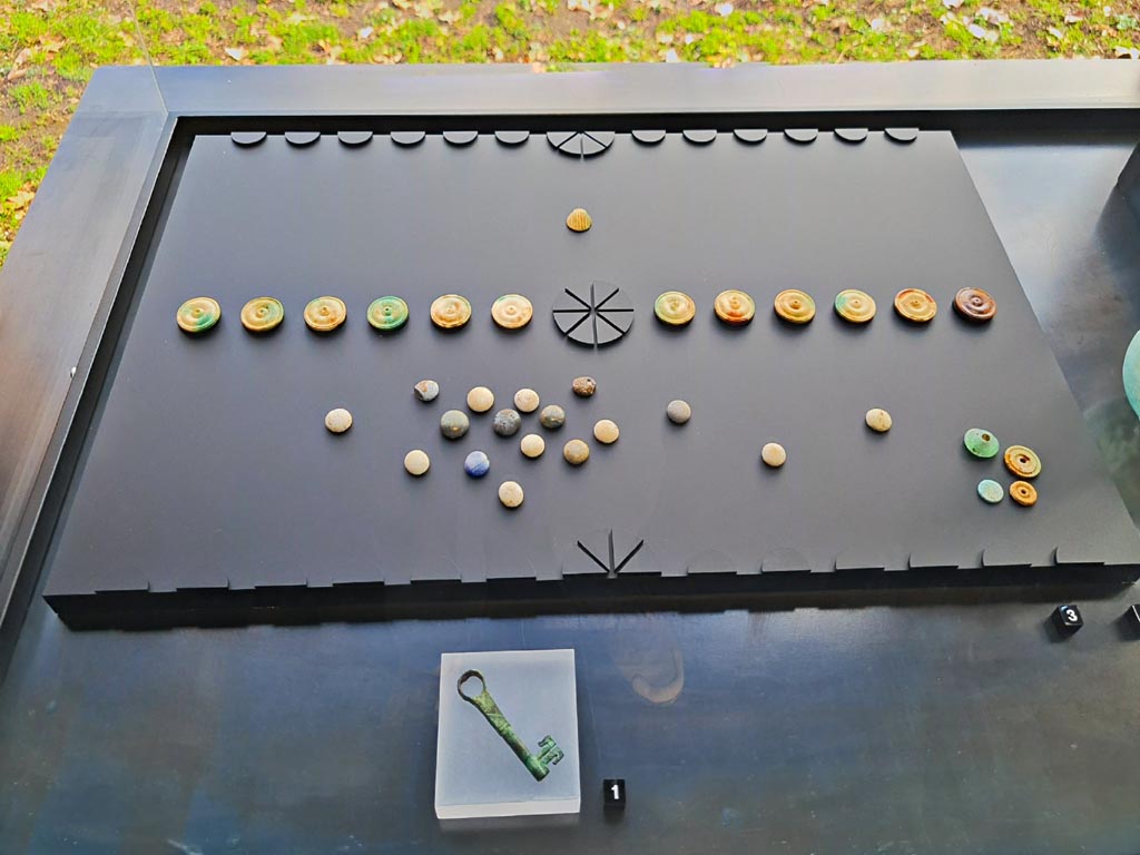 I.13.5 Pompeii. March 2024. Items found in a wooden crate in rear room. Photo courtesy of Giuseppe Ciaramella.
1. Bronze key.
3. Game set.
On display in exhibition in Palaestra entitled – “L’altra Pompei, vite comuni all’ombra del Vesuvio”.
