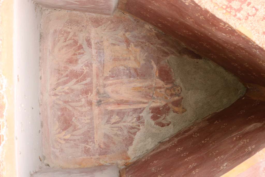 I.14.7 Pompeii.  March 2009.  Garden area, west wall.  Niche Lararium with painting of a god in a long white robe lying on a couch.  The right hand holds a branch and the left holds a Patera.  To the right is a golden candelabrum.  At the front is a three legged table with a bowl of fruit.  Above is a garland. See Fröhlich, T., 1991. Lararien und Fassadenbilder in den Vesuvstädten. Mainz: von Zabern. (L34, T:29,3)