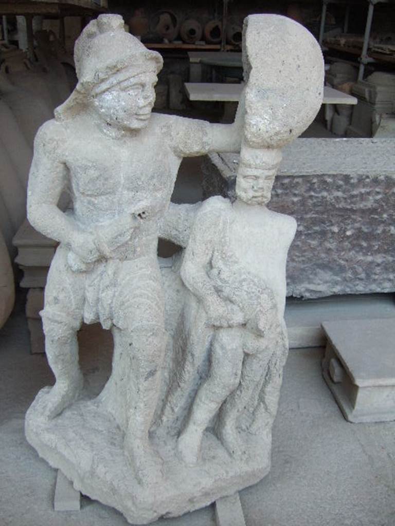 .20.1 Pompeii. Inn of the Gladiators and vineyard.
Statue of a gladiator with a sword and shield protecting another (Priapus?).
Found on a base near the triclinium.
See Jashemski, W. F., 1979. The Gardens of Pompeii. New York: Caratzas. P: 178, T: 264.
Now in the Forum Granary store at VII.7.29. SAP Inventory number 11739.