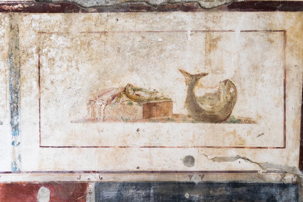 II.1.12 Pompeii. July 2021.
Triclinium, upper panel on west wall at north end, with wall painting of fishes. Photo courtesy of Johannes Eber.