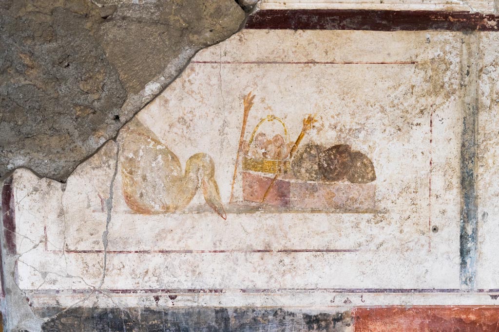 II.1.12 Pompeii. July 2021.
Triclinium, upper panel on west wall at south end, with painting of a swan, a basket and two torches. Photo courtesy of Johannes Eber.