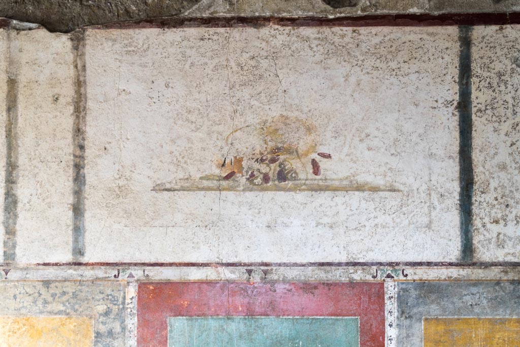 II.1.12 Pompeii. July 2021.
Triclinium, upper panel from centre of south wall with painting of a fallen basket and dates. Photo courtesy of Johannes Eber.