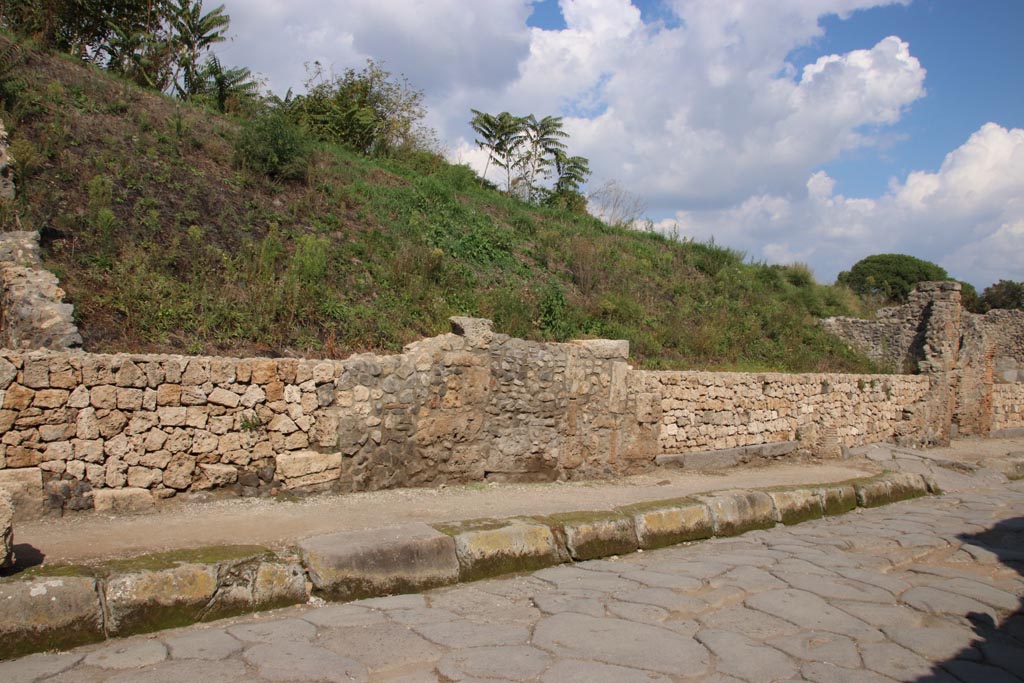 III.7.3 Pompeii. October 2022. Continuation from previous photo, see III.7.1. 
Looking east along front façade towards the doorway with the ramp at its entrance, on the extreme right of the photo.
The shop at III.7.2 with the large grey lava doorway threshold can be seen on the west (left side) of the ramped entrance.
Photo courtesy of Klaus Heese
