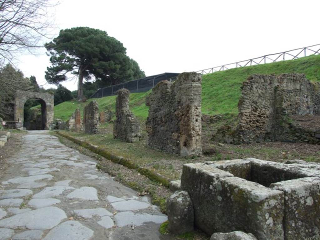 III.11.1 Pompeii. March 2009. Via Nola looking east to Nola Gate, taken outside III.11.1 and fountain. The blocked vicolo at the rear of the fountain leads to entrance III.11.a
