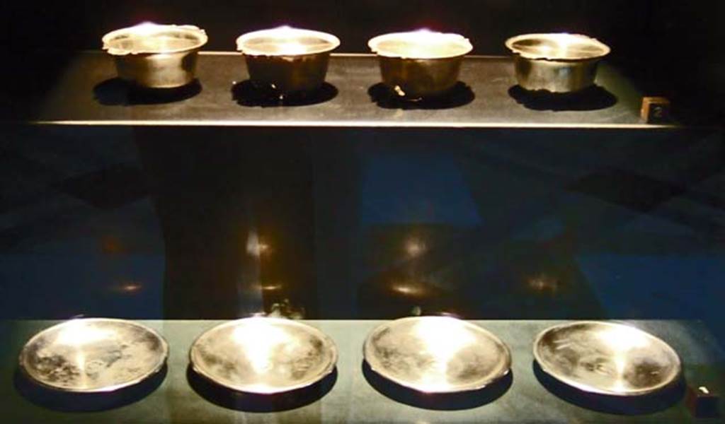 V.1.18 Pompeii. Set of four silver plates and cups. Found in the ala “e”.
Now in Naples Archaeological Museum.
Four silver cups with short conical bodies. Inventory numbers 110846, 110847, 110848, 110849.
Four silver plates with 5 petal rosettes in the centre. Inventory numbers 110842, 110843, 110844, 110845.