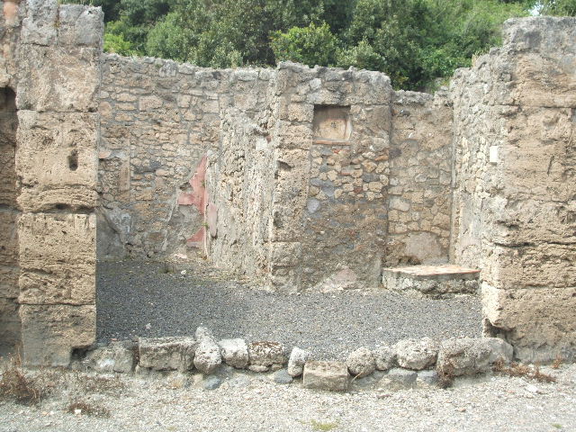 V.2.14 Pompeii. March 2009. Niche Lararium in north wall of shop. According to Boyce, this niche had a projecting floor and its inside walls were coated with white stucco and outlined with red stripes. He also mentioned that in Mau’s description of V.2.13, a cylindrical altar of travertine was found in the rear room. Boyce thought there was confusion between the text and the plans of the rooms, and in fact the altar was found in V.2.14. When the book was written, the altar was on display in V.2.14. However, the Not.Scavi, 1896, 438, does not record the discovery of this altar.
See Boyce G. K., 1937. Corpus of the Lararia of Pompeii. Rome: MAAR 14. (p.34, no.93)