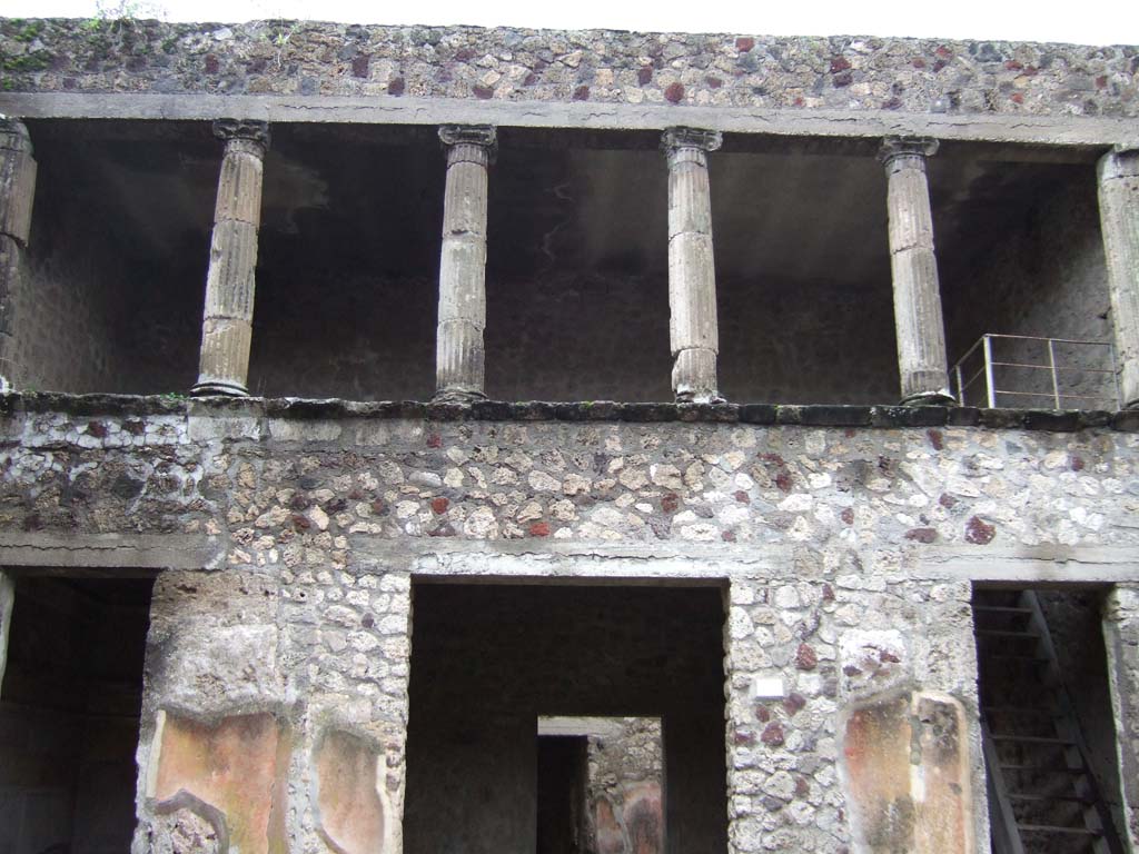 V.2.h Pompeii. December 2005. Upper floor cenaculum with columns, looking south across atrium.
According to NdS, in the atrium several parts of tufa fluted columns were found.
They were of various sizes, with bases and Ionic capitals.
According to Sogliano, Mau believed that the said Ionic columns belonged to a portico above the rooms ‘e’, ‘f’ and ‘g’, which would have been open onto the rear side of the atrium.
In 1896 Sogliano thought this was certainly possible, as was seen in other places in Pompeii, but he would not confirm this with certainty, considering above all the lack of robustness of the supporting walls.
See Notizie degli Scavi di Antichità, 1896, (p.422).
See Mau in Bullettino dell’Instituto di Corrispondenza Archeologica (DAIR), VIII, 1893, (p.16)
By 1903, Sogliano agreed with Mau, as he wrote that “it was noted that above the tablinum and the two adjacent rooms was a portico or loggia open onto the atrium”.
See Sogliano in Atti del Congresso Scienze e Storiche, 19/4/1903, (p.322)